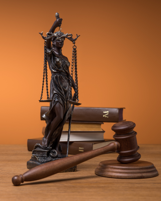 bronze statuette with scales of justice, gavel and books on wood
